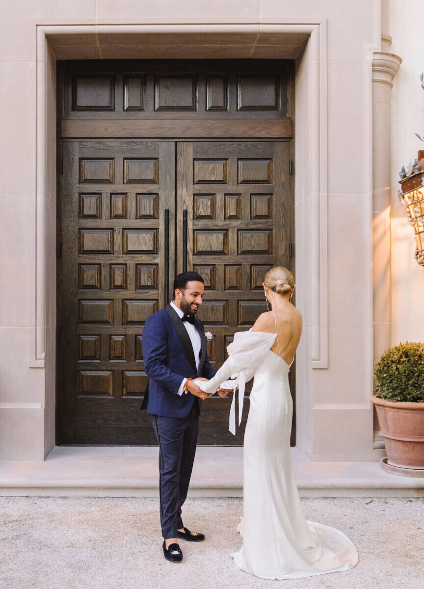 A couple shares a first look once they changed into a tux and wedding gown at their Indian fusion wedding.